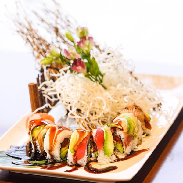 Kirin Asian Cuisine & Sushi's Dragon Roll, topped with avocado, tuna, and eel sauce, garnished with flowers.