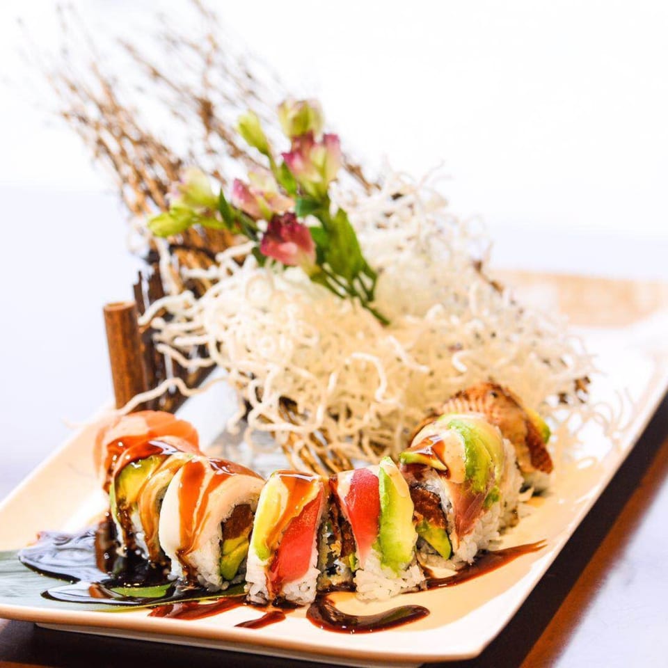 Kirin Asian Cuisine & Sushi's Dragon Roll, topped with avocado, tuna, and eel sauce, garnished with flowers.