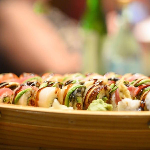 Assorted sushi rolls with avocado, fish, and sauce, served in a wooden boat at Kirin Asian Cuisine.